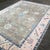 A refined Turkish Oushak rug featuring a warm Makara brown field framed by a soft pink border, with large-scale floral...
