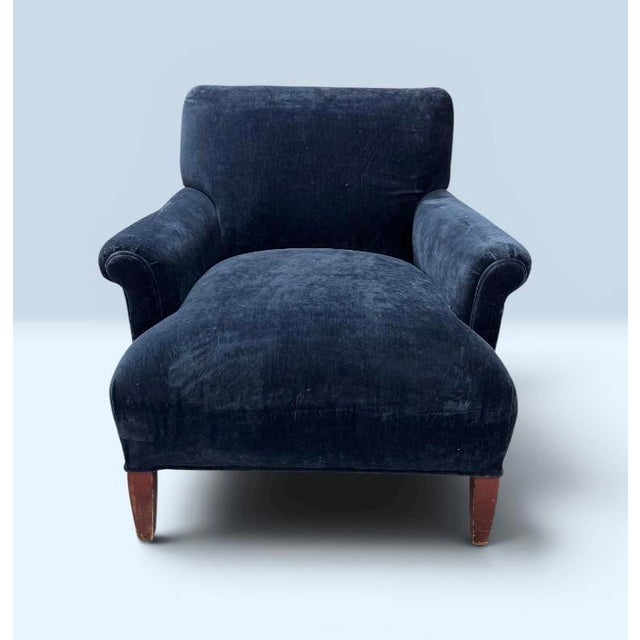 A vintage accent chair featuring deep blue velvet upholstery, a pleated sock arm design, and tapered wooden legs. A Very...