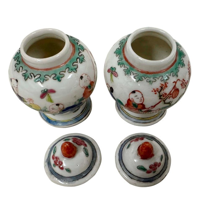 This pair of Chinese export porcelain ginger jars decorated in the famille rose palette. They depict scenes of figures,...