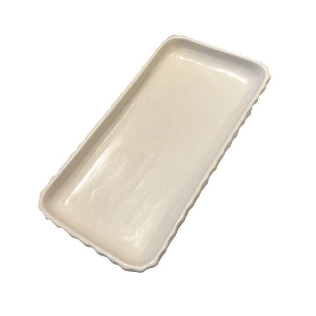 A vintage soft ivory-white ceramic tray in a matte finish, by Waterworks. This unique tray has a feminine curved...