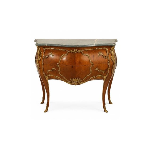 A Louis XV style commode of bombe serpentine form. Two drawers are veneered sans traverse in quarter-matched figured wood,...