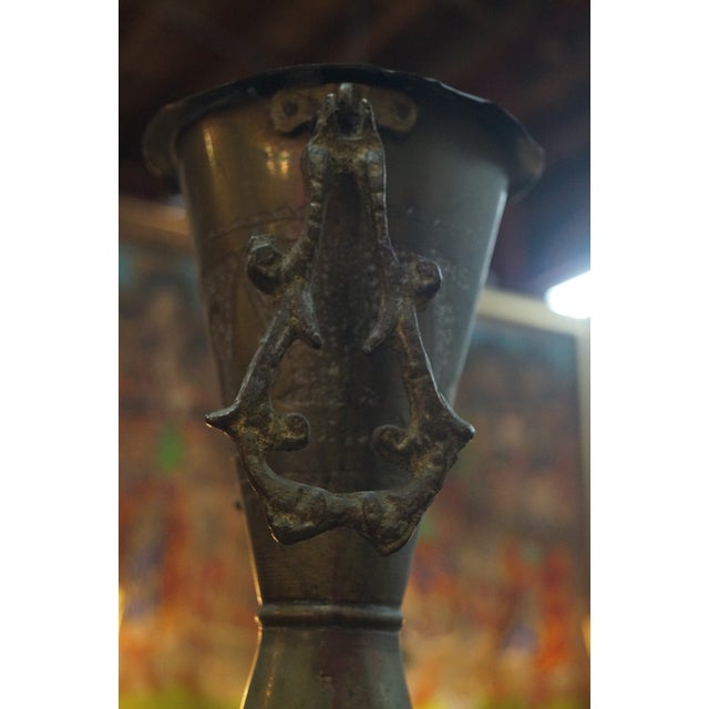 A tall vintage Persian vase with striking handles that dangle on the sides and an embosses and etched body. Measures 22...
