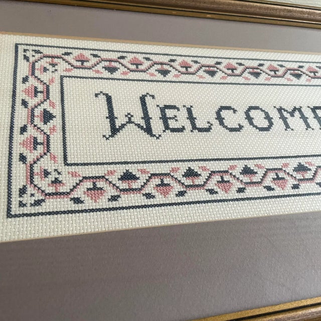 Gold framed cross stitch welcome sign. This item could easily be repurposed into a pillow, if you’re crafty. In its...