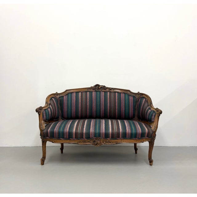 An elegant vintage Louis XV-style settee featuring a beautifully carved walnut frame with graceful cabriole legs,...