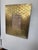 A decorative wall frame with a richly textured brass surround. Rows of rounded, interlocking shapes create a woven effect,...