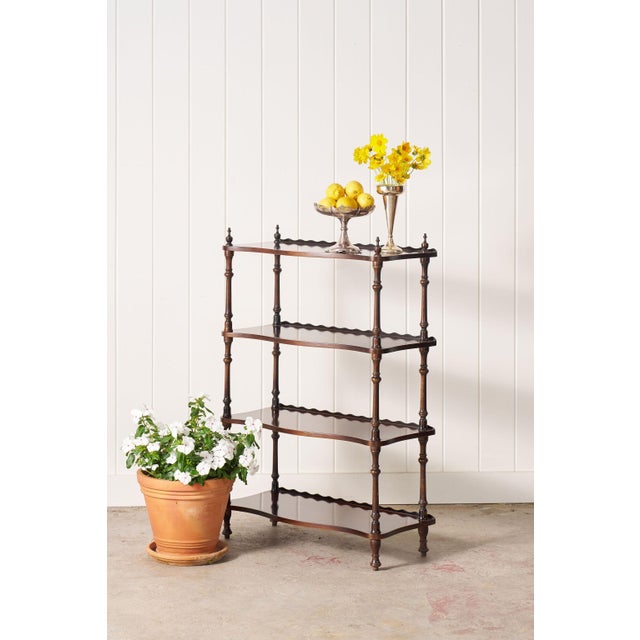 Antique English mahogany bookshelf with serpentine shelves, a scalloped back, and open three-tier design.