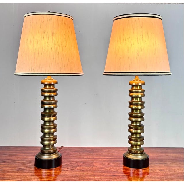 A pair of very large, sculptural and dramatic mid century modern table lamps with aged brass finish and black painted...