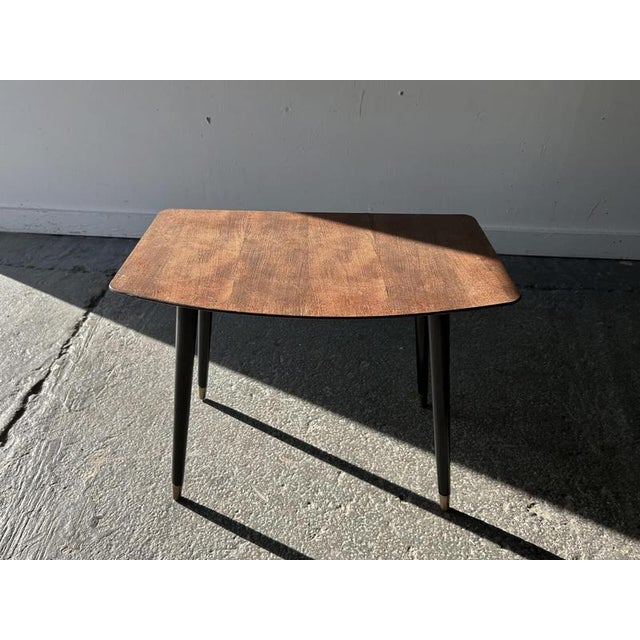 A compact Mid-Century occasional table featuring a solid timber plank-effect top with softly rounded corners and gently...