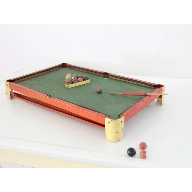 A C.G. Wood Co. “Modern Boy” toy billiards set, circa 1918–1923. The table features a red and yellow metal frame with the...