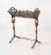 Elegant Art Nouveau cast iron book rack featuring pierced decorative motifs, figural harlequin side supports, and a...