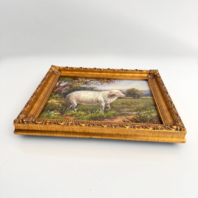 A signed pastoral landscape with a sheep grazing in a wildflower field. Framed in a gold frame. Illegibly signed. Size:...