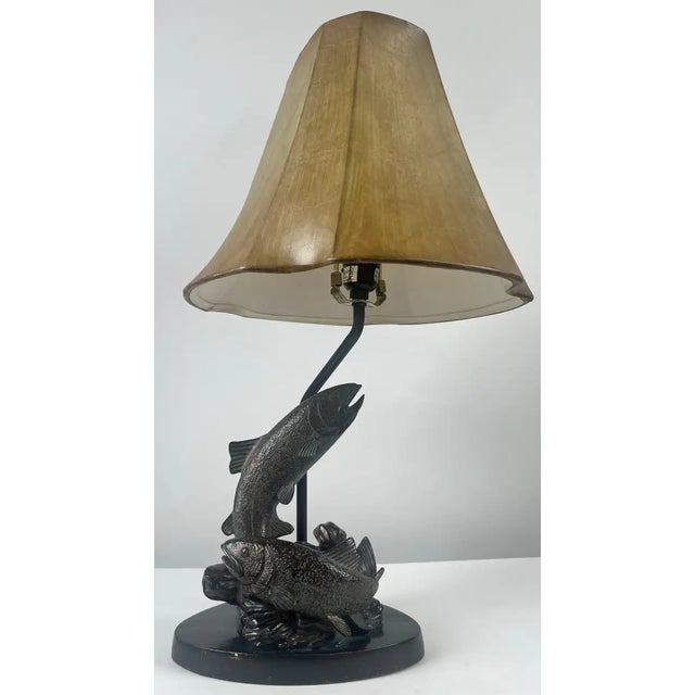 This rustic fishermen cabin table lamp features a sculptural base depicting a flying trout in dynamic motion, crafted from...