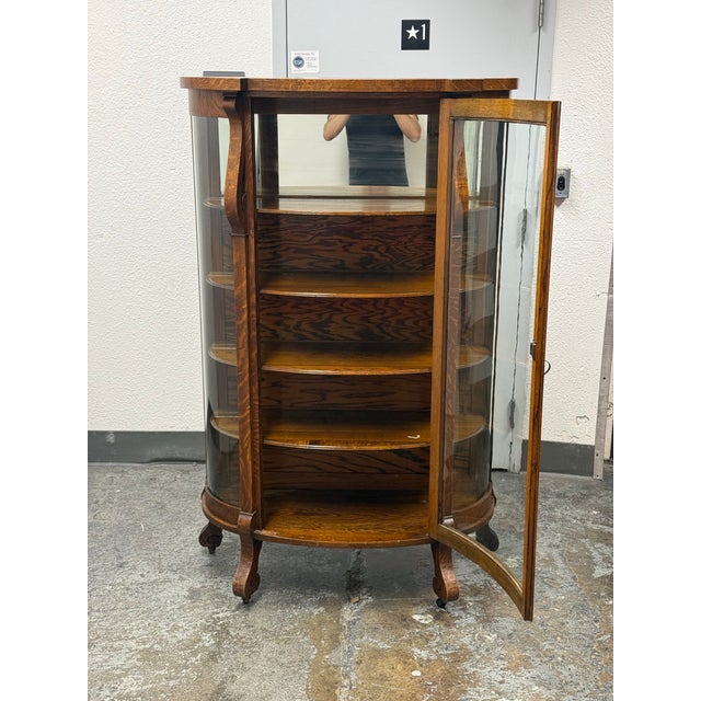 Design Plus Gallery presents an Antique Victorian Quarter-Sawn Tiger Oak Curved Glass Curio. The cabinet displays...