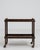 A circa 1960 French bar cart constructed in wood, featuring a rectangular frame with open shelving and mounted on casters....