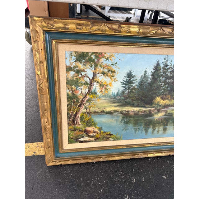 This is a vintage oil painting on canvas featuring a serene lakeside landscape with a dense forest. The double-layered...