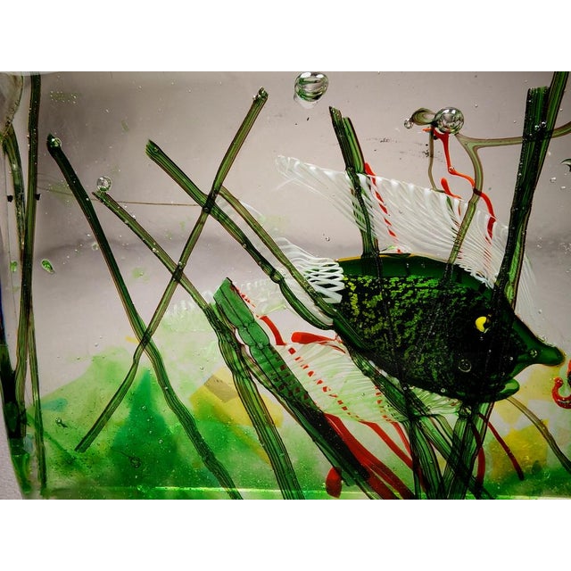 A stunning murano glass block depicting fish and marine plants in clear glass. The sculpture is crafted from clear glass...