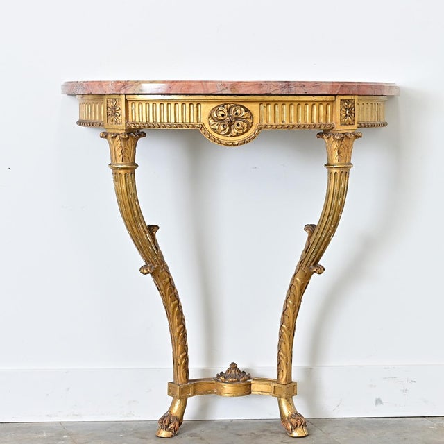 A dramatic 19th century Neoclassical demilune-console from France, with an exquisite giltwood base supporting an...