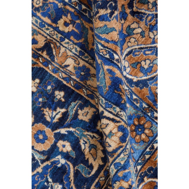 An early 20th century Persian Kerman rug the steel blue field with a large palmette, rosette and flowering vinery trellis...