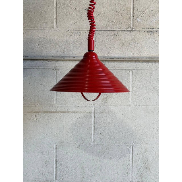 This vibrant hanging pendant fixture features a striking red metal shade with a unique ribbed design and an adjustable...