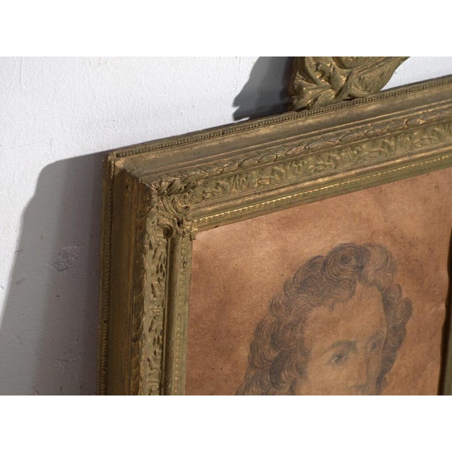 Antique pencil portrait in gilded frame, on parchment-toned paper, set in a gilt stucco moulding with a heraldic crest of...
