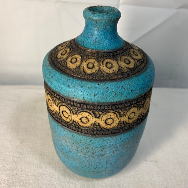 The vase showcases a classic textured turquoise blue or teal glaze combined with hand-carved or incised concentric circle...