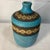 The vase showcases a classic textured turquoise blue or teal glaze combined with hand-carved or incised concentric circle...