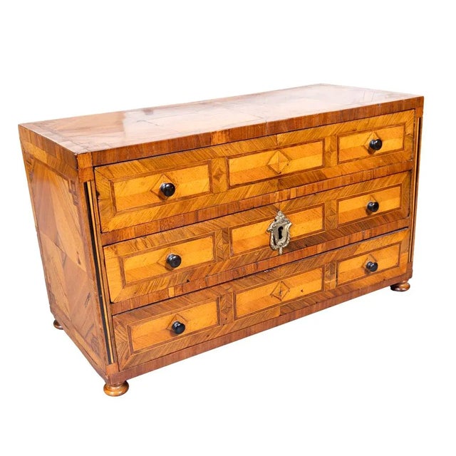 Rectangular top over three drawers with wood knobs and escutcheon. Bun feet.