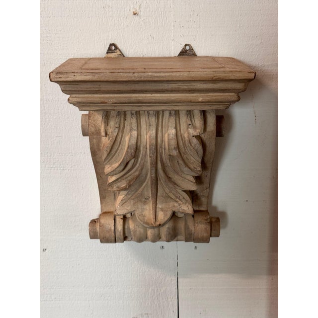 Pair of carved wood wall brackets with molded shelf tops over bold acanthus leaves and scrolled sides, in a pale bleached...