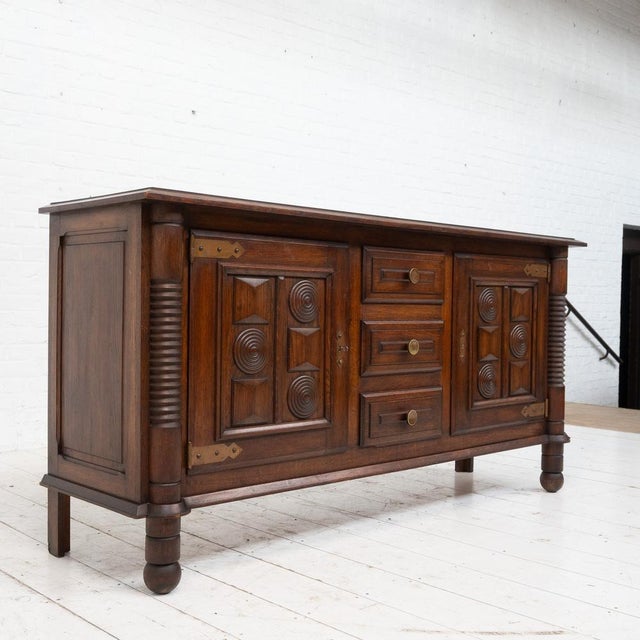Oak sideboard in the style of Charles Dudouyt, France - 1940 Two doors opening onto a series of shelves. Three central...