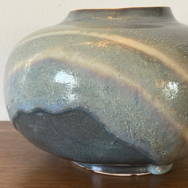 Large hand thrown studio pottery lidded jar featuring a flowing crystalline glaze in shades of gray, blue, and cream....