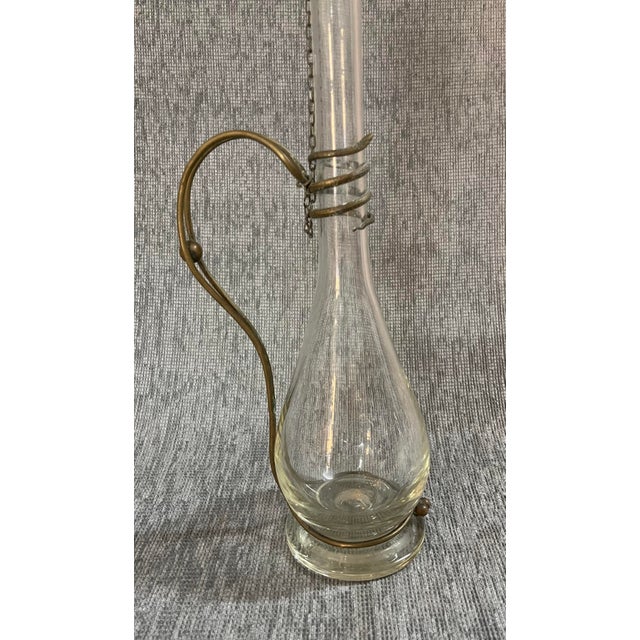 Beautiful blown glass decanter bottle. It features elegant brass appliqués representing a snake on the body and an...