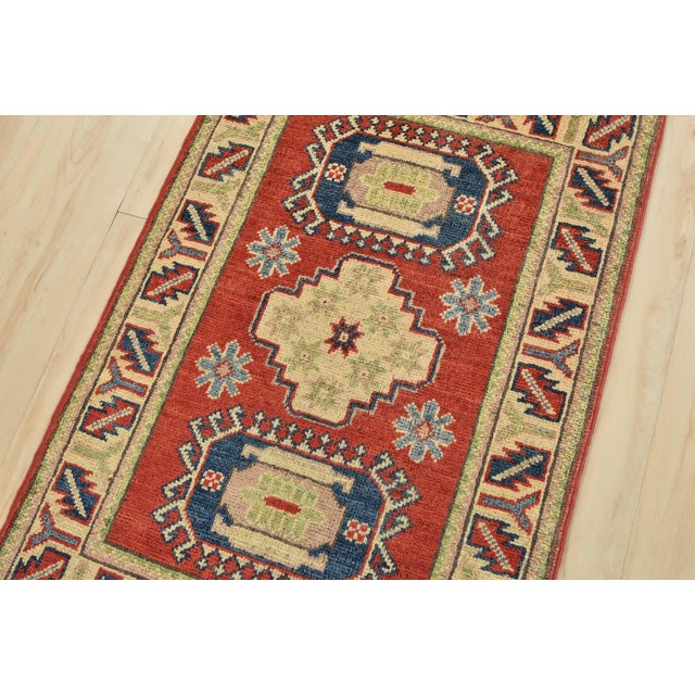 A tribal Caucasian Kazak rug hand-knotted with an all-wool pile on a cotton foundation. This oriental rug features...