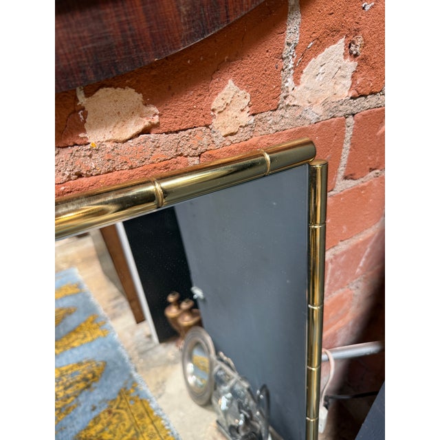A refined Italian Mid-Century Modern wall mirror featuring a polished brass frame designed to emulate bamboo canes. The...