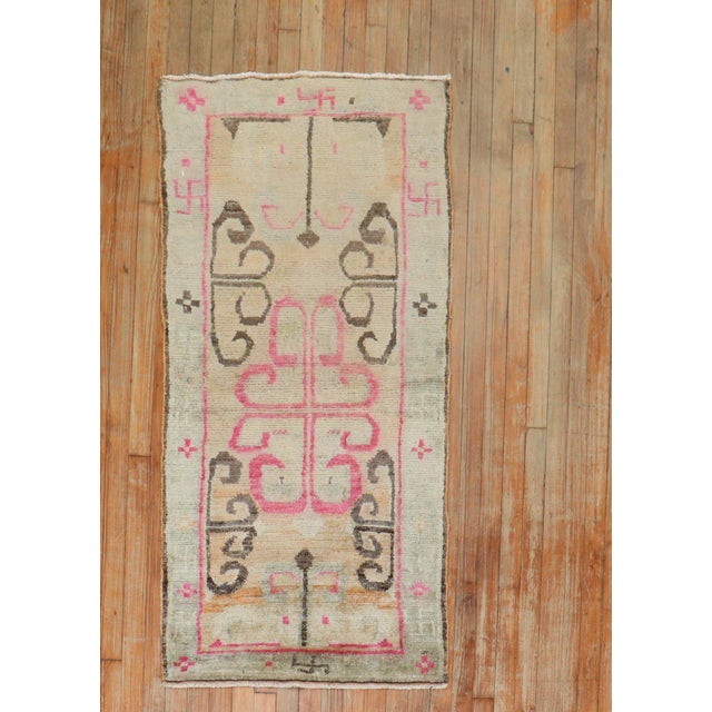 2nd Quarter of the 20th century Tibetan Rug in feminine colors. The border consists soft brown, pink and white swastikas...
