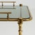 A circa 1960 French bar cart in the Hollywood Regency style, crafted in brass and mounted on wheels. The structure...