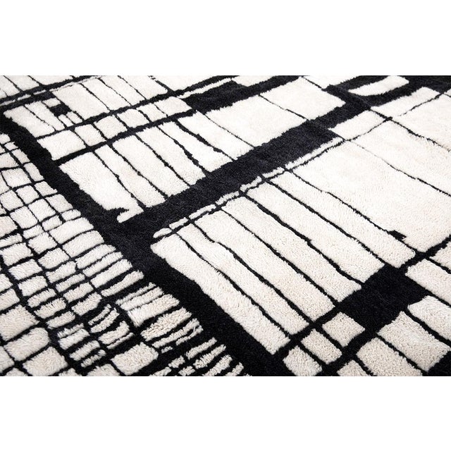 A striking hand-knotted wool rug featuring a bold architectural abstract design in refined Soft Cream and deep Jet Black....