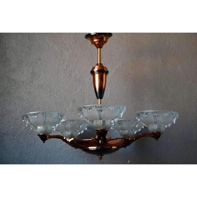 Made up of metal supports with copper reflections and carrying large frosted glass cups, this large Art Deco style...