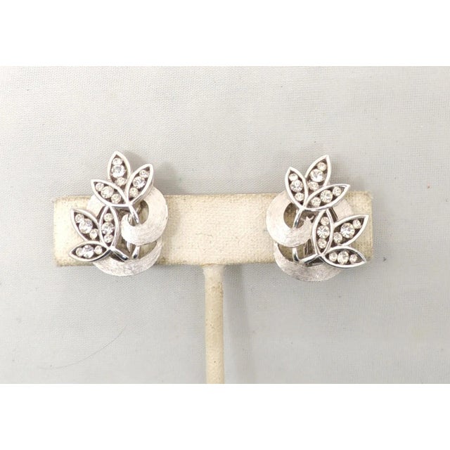 This is part of Chairish’s Costume Jewelry assortment. Rhodium plated round clear rhinestone flower clip earrings. Marked...