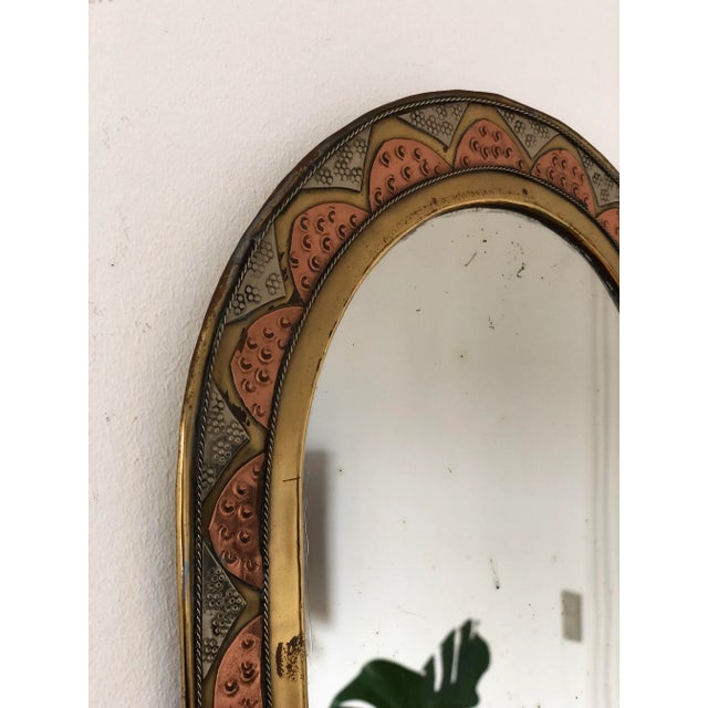 Vintage decorative wall mirror from Spain with an arched shape and a brass-toned frame with copper-colored and silver-...