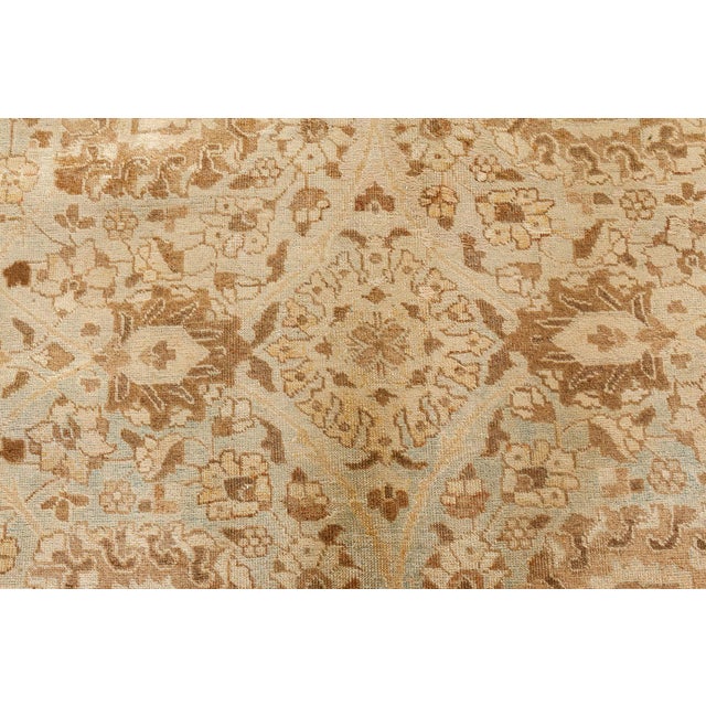 An early 20th century Persian Tabriz rug, the abrashed celadon green field with an allover trellis of palmettes and...