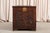 A carved oak chest in the Jacobean Revival style. The front panel has scrolling acanthus leaves around a central oval...