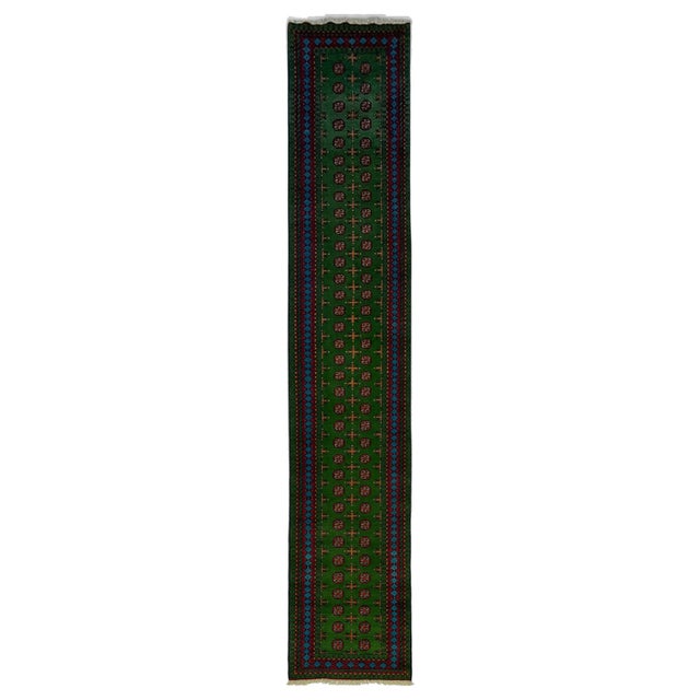 This long runner features a rich green field with two rows of repeating geometric medallions and small cross motifs....
