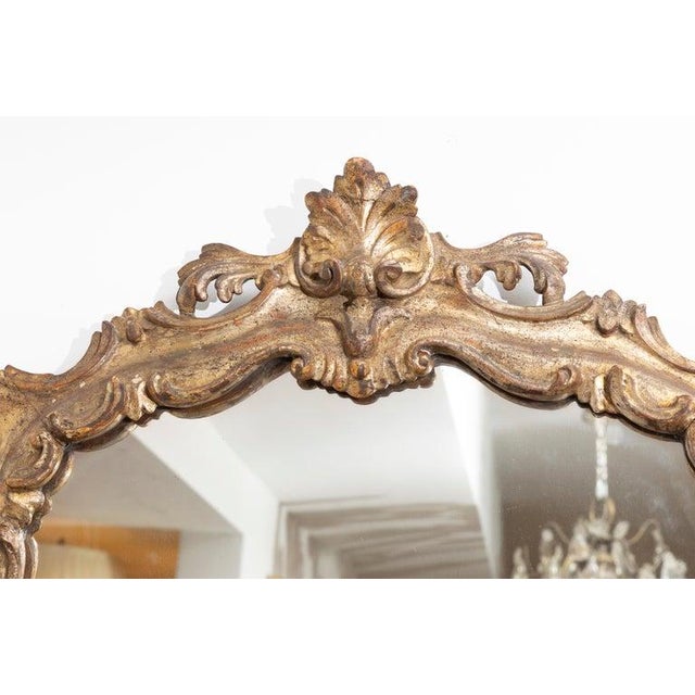 This is an elegant Italian Rococo-style wall mirror featuring a richly carved giltwood frame with exuberant scrolling...