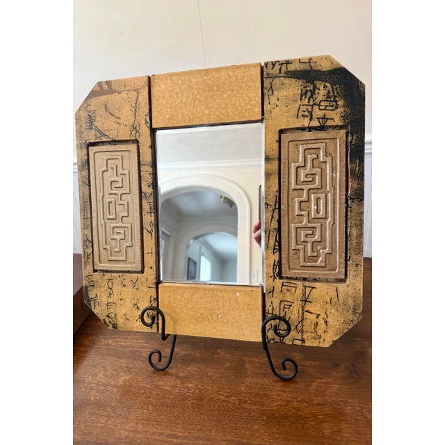 The most distinctive feature of this vintage framed mirror is the raised, intricate Greek key or labyrinthine pattern...
