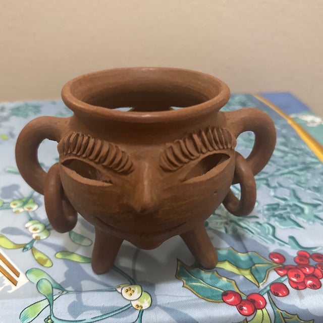Bring a touch of Central American tradition to your home with this striking handcrafted terracotta face vessel. Known as...
