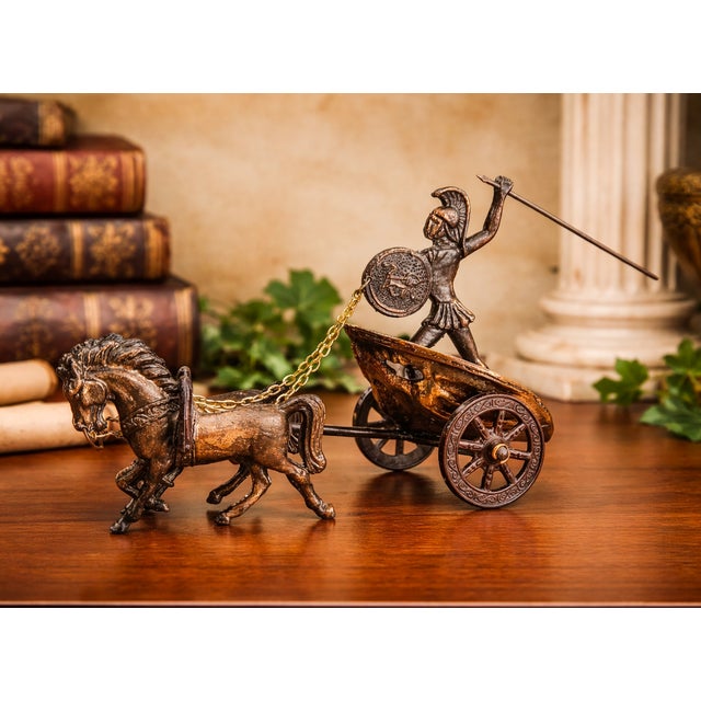 A striking vintage bronze sculpture depicting a Roman warrior standing in a two-wheeled chariot drawn by two horses....