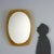 Oval-shaped wall mirror with an orange glass frame; the manufacturer's logo is on the back. This piece is attributed to...