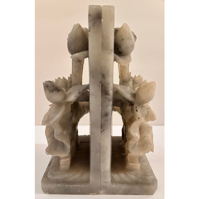 A pair of carved stone bookends featuring raised flower motifs, each panel showing a full bloom flanked by budding stems...