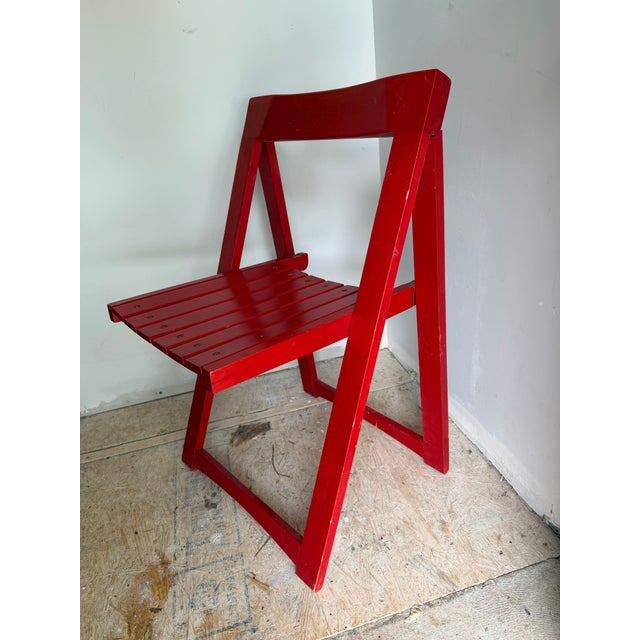 Mid-century modern vintage folding wooden chair in fire-engine red with brass fasteners. Such a cool piece that would be...