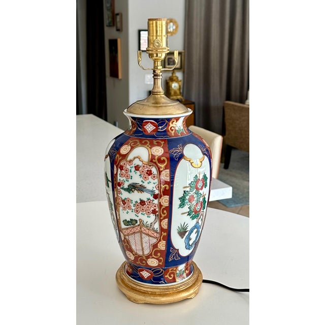 Single Japanese Imari porcelain vase mounted on giltwood base with brass vase cap. The colors are classic Imari in rich...